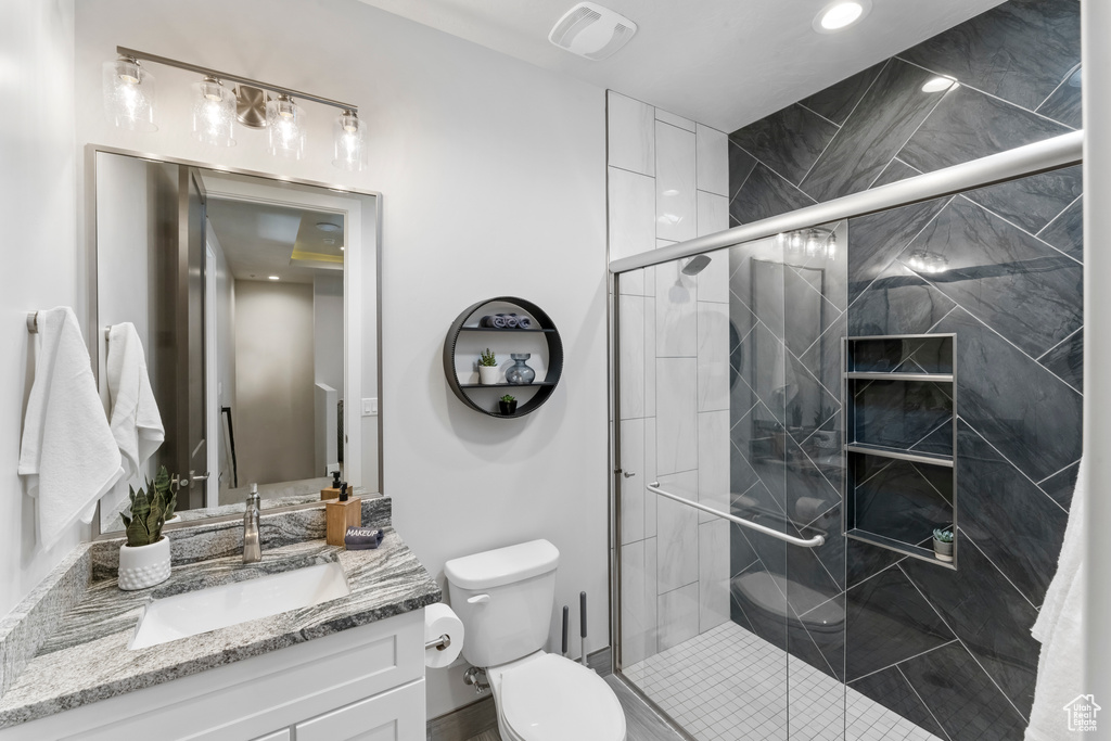 Bathroom with a shower with shower door, toilet, and vanity