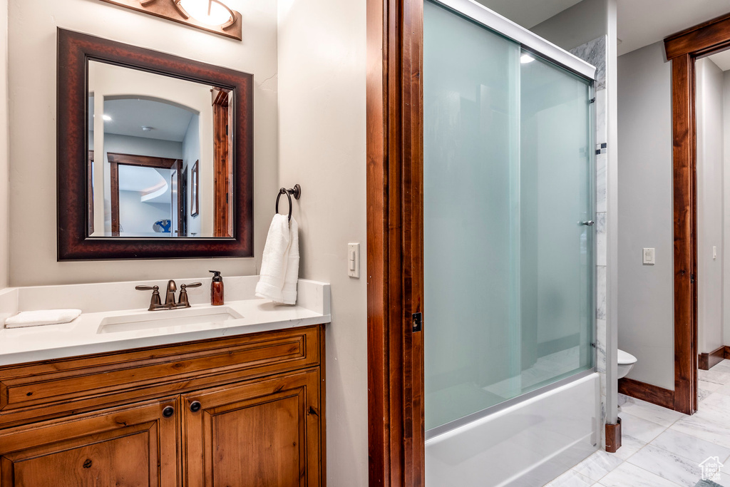 Full bathroom featuring tile patterned flooring, combined bath / shower with glass door, toilet, and vanity