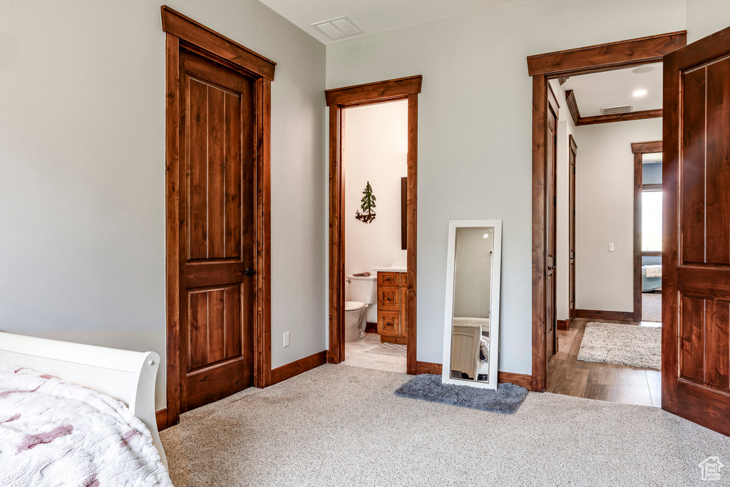 Bedroom with ensuite bathroom, wood-type flooring, and crown molding