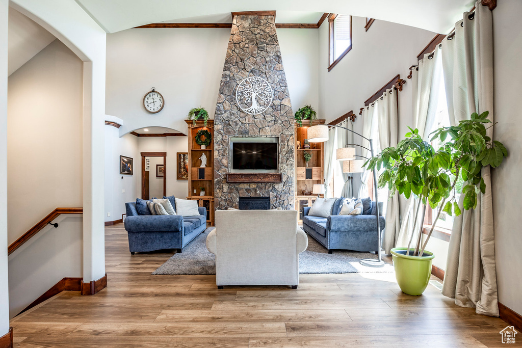 Living room with wood-type flooring, a fireplace, and a towering ceiling