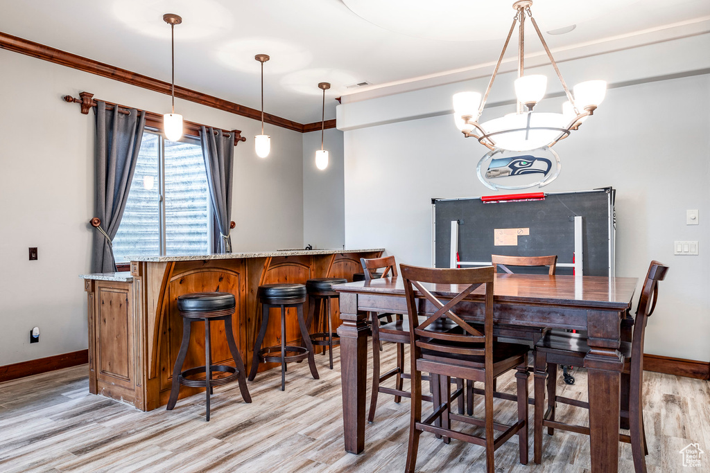 Dining space with an inviting chandelier, light hardwood / wood-style flooring, and ornamental molding