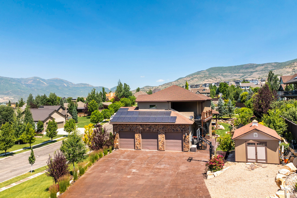 Front facade with a storage shed, a mountain view, a garage, and solar panels