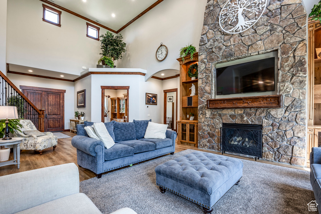 Living room featuring high vaulted ceiling, a fireplace, crown molding, and hardwood / wood-style floors