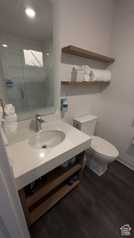 Bathroom featuring vanity, toilet, a tile shower, and hardwood / wood-style floors