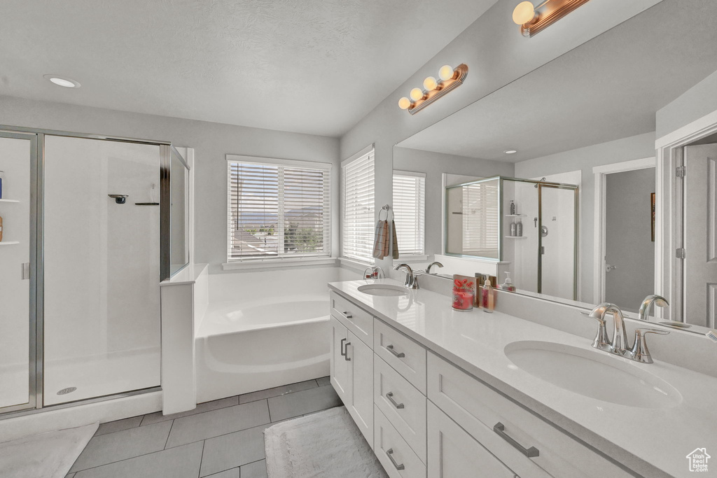 Bathroom with tile patterned flooring, shower with separate bathtub, a textured ceiling, and dual bowl vanity