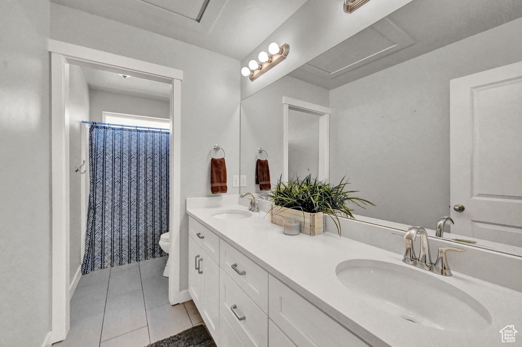 Bathroom featuring tile patterned flooring, dual bowl vanity, and toilet