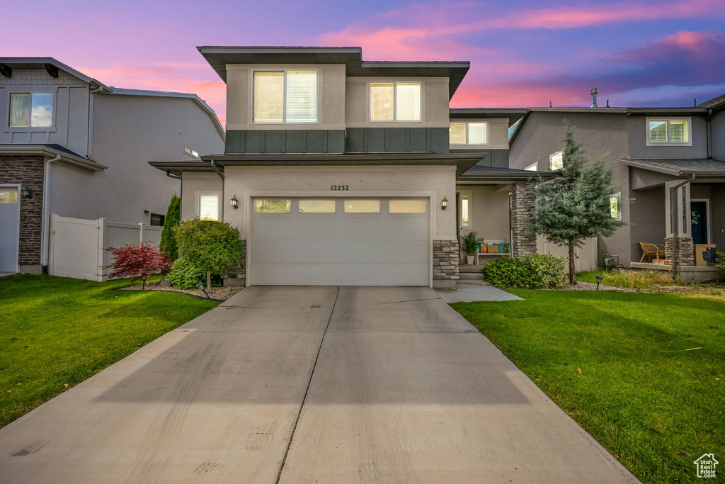 View of front of property featuring a garage and a yard