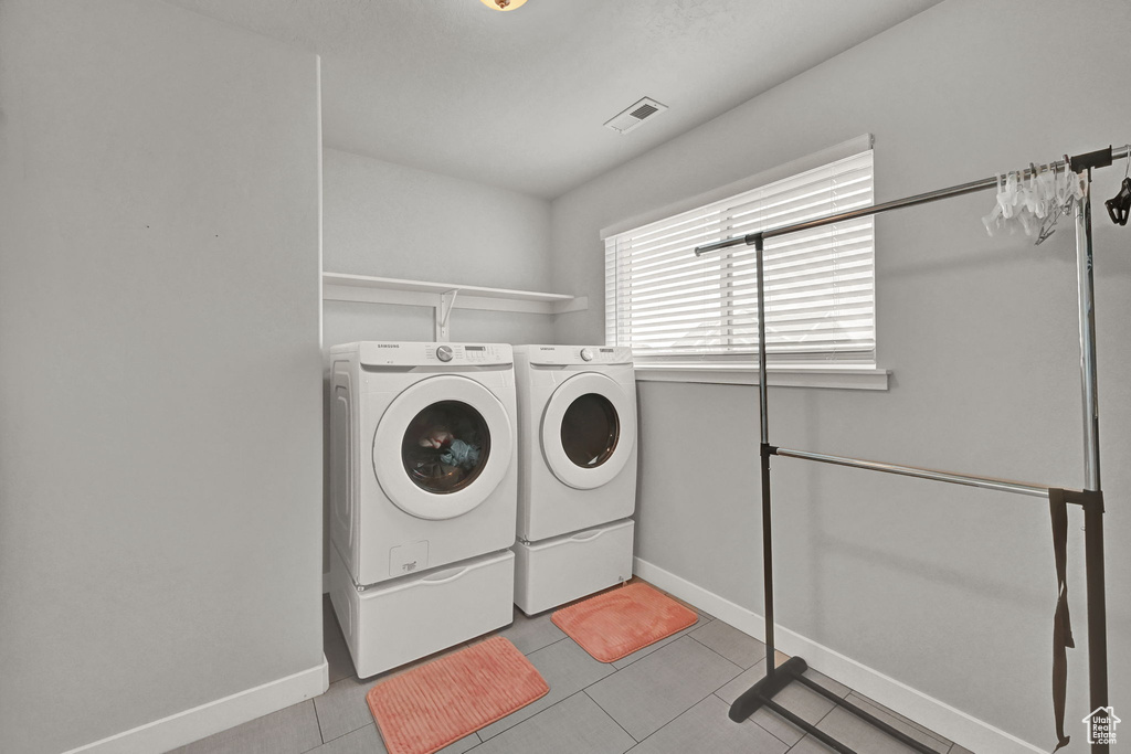 Clothes washing area featuring washing machine and dryer and light tile patterned floors