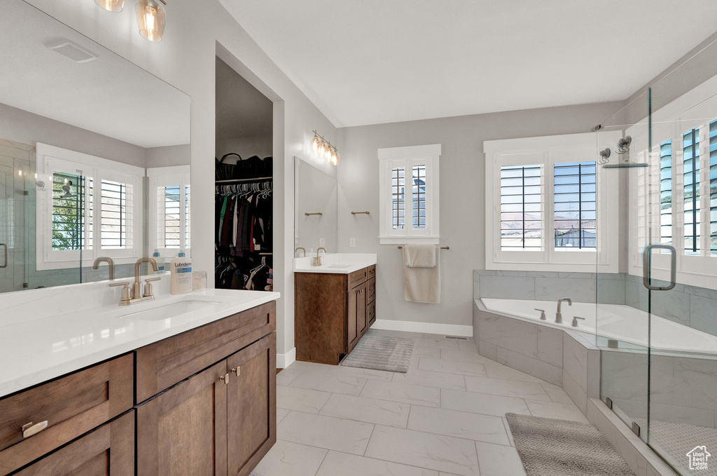 Bathroom featuring tile patterned flooring, shower with separate bathtub, and double vanity