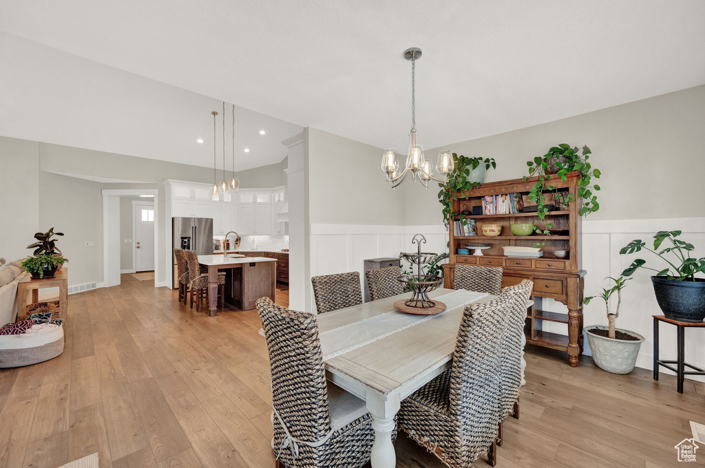 Dining room featuring light hardwood / wood-style floors, sink, and an inviting chandelier