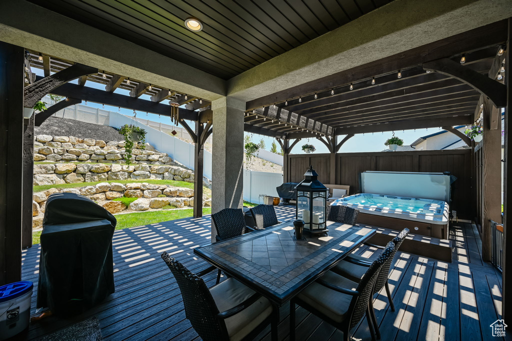 Wooden terrace with a pergola and a hot tub