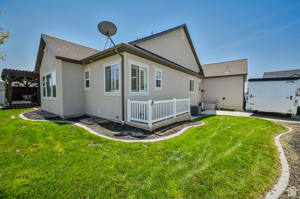 Back of house featuring a pergola, central air condition unit, and a lawn