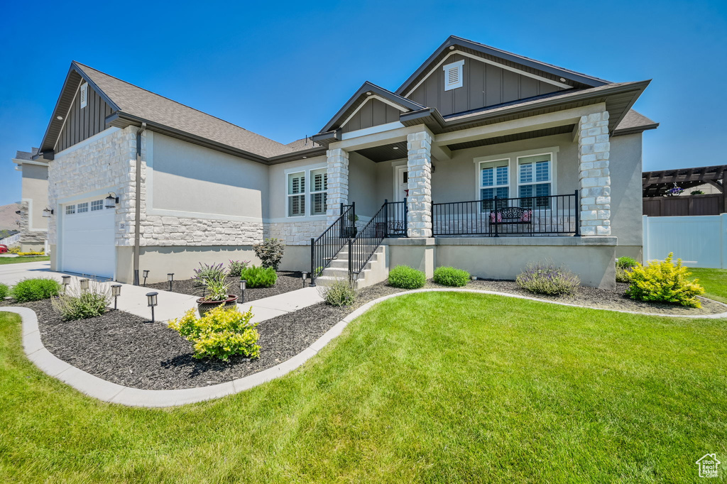 View of front of property featuring covered porch, a garage, and a front lawn