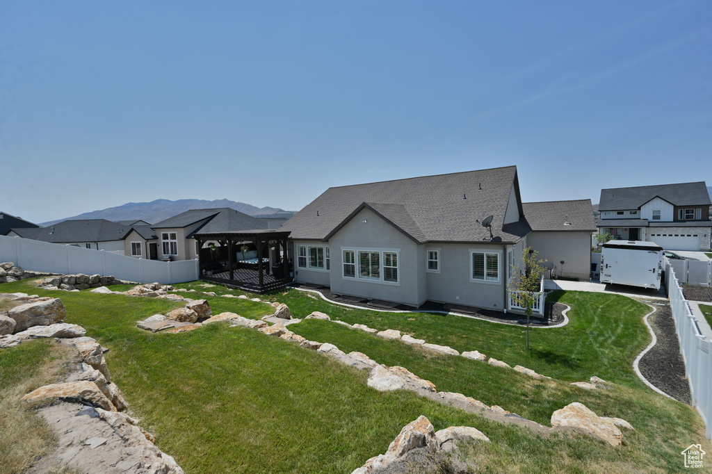 Rear view of property featuring a garage, a mountain view, and a lawn