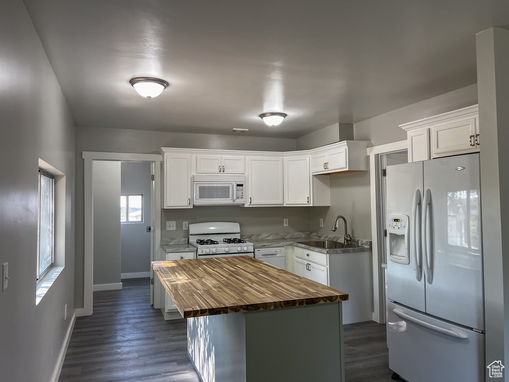 Kitchen with sink, dark hardwood / wood-style floors, white appliances, and white cabinets