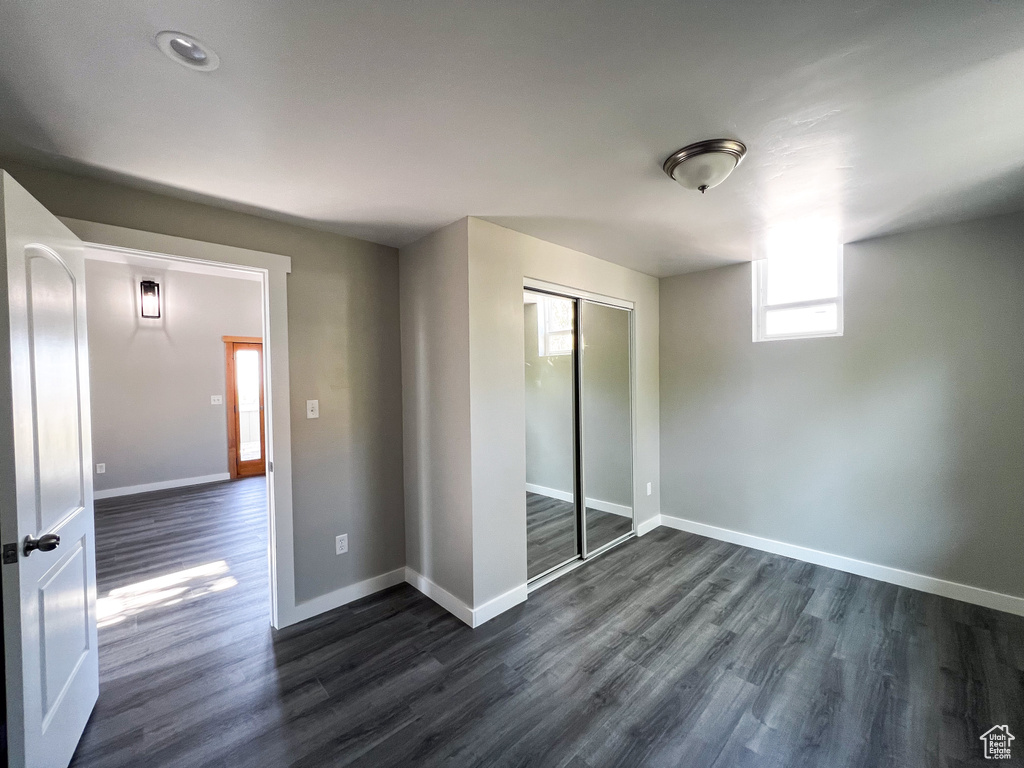 Unfurnished bedroom featuring dark wood-type flooring and a closet