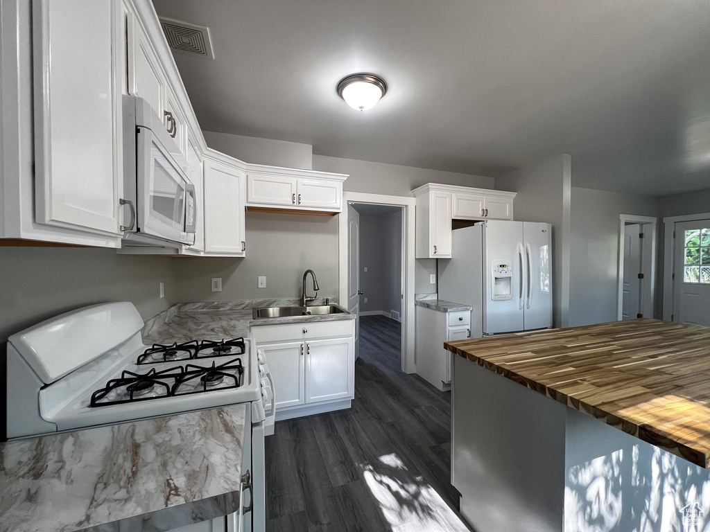 Kitchen with white cabinets, dark hardwood / wood-style flooring, white appliances, and sink