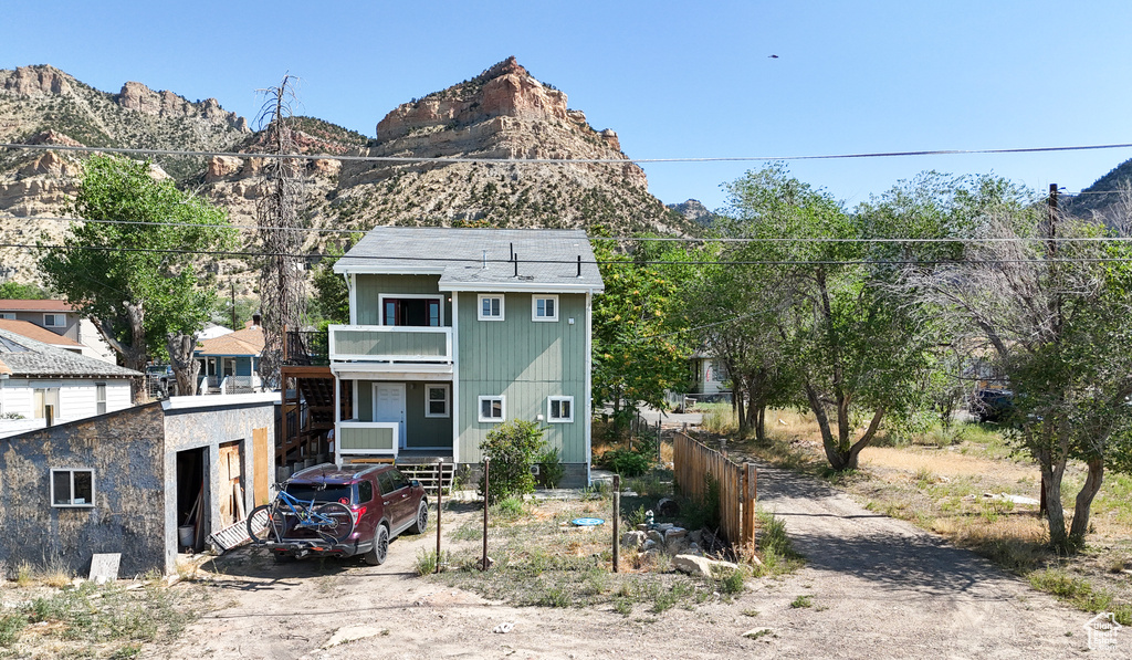 Rear view of property with a mountain view and a balcony