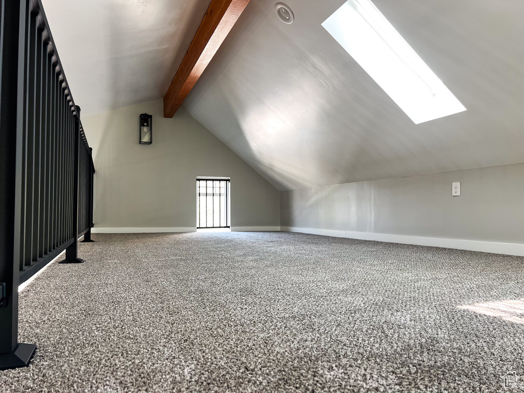 Additional living space with carpet floors and lofted ceiling with skylight