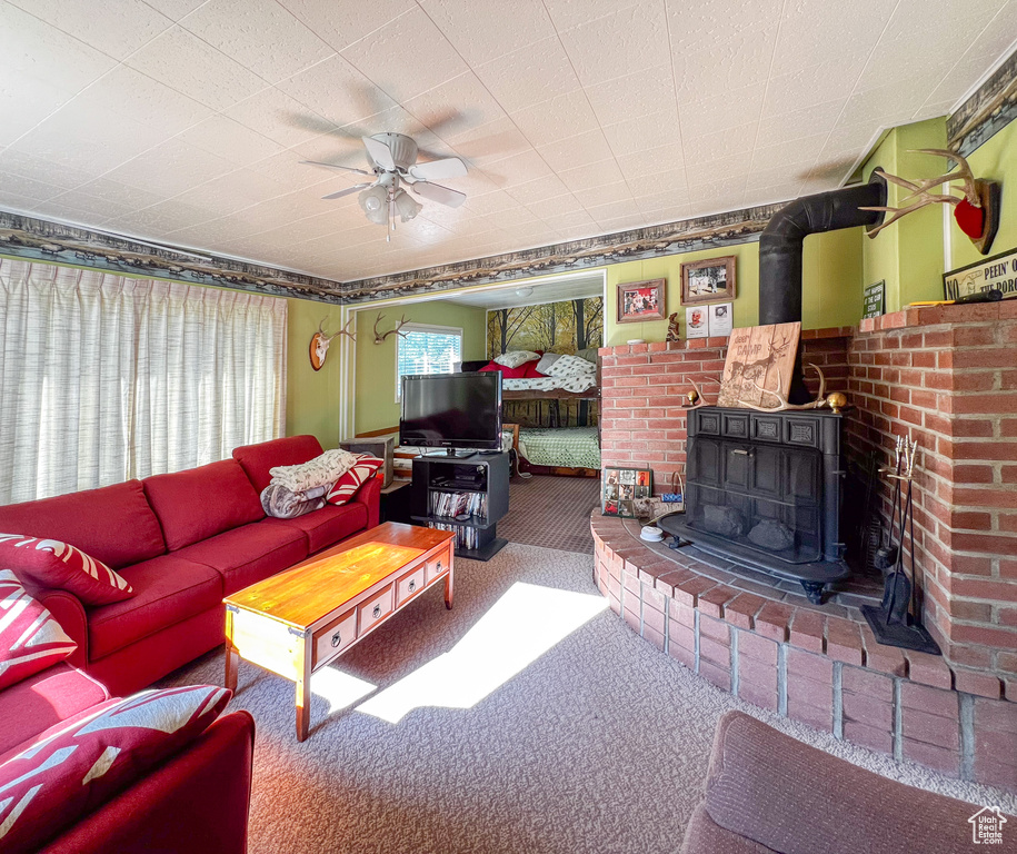 Living room featuring a wood stove, carpet, and ceiling fan