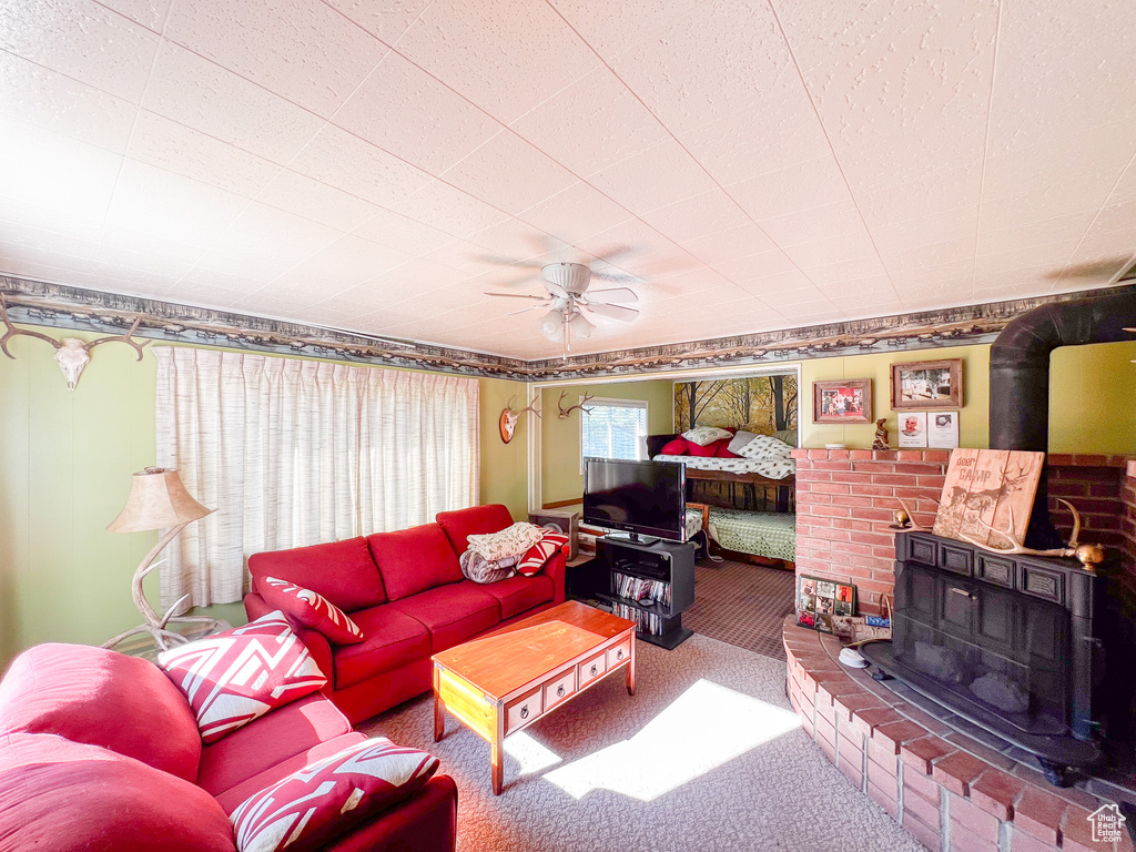 Carpeted living room featuring ceiling fan and a wood stove