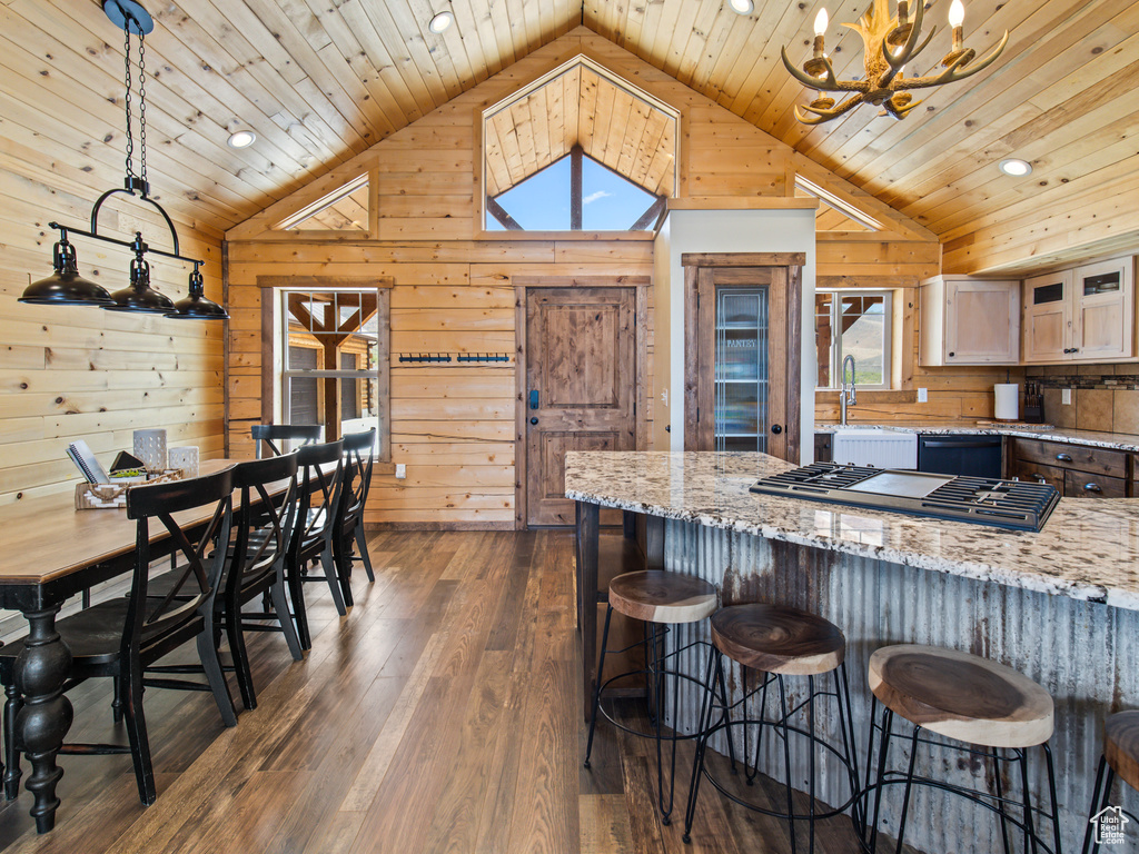 Kitchen with decorative light fixtures, dark hardwood / wood-style flooring, a wealth of natural light, and light stone counters