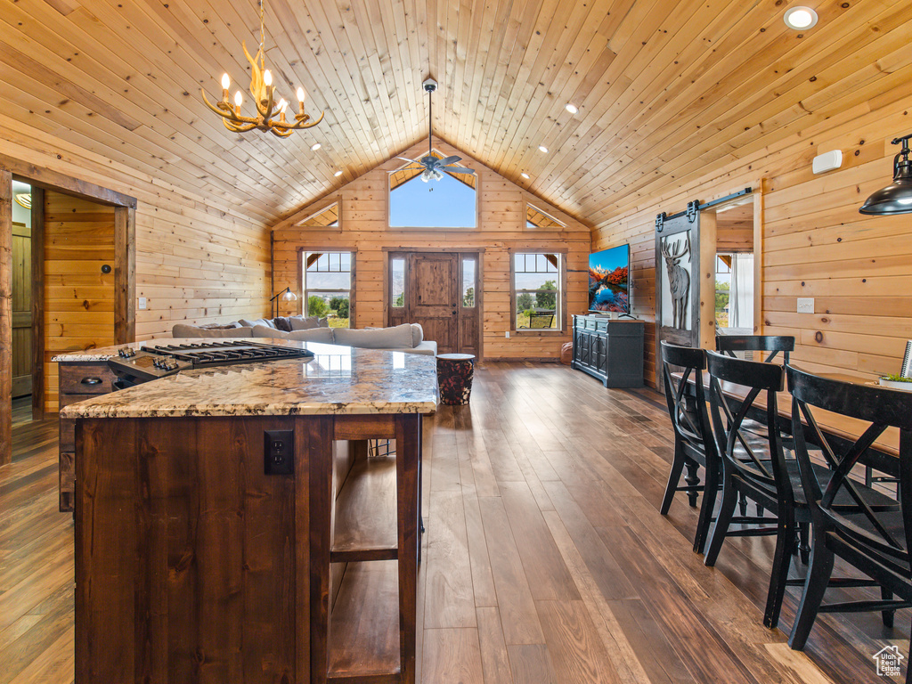 Kitchen with hanging light fixtures, a barn door, dark hardwood / wood-style floors, wood walls, and wooden ceiling