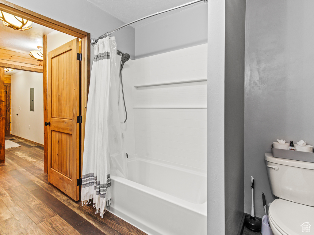 Bathroom with shower / tub combo with curtain, toilet, and hardwood / wood-style floors