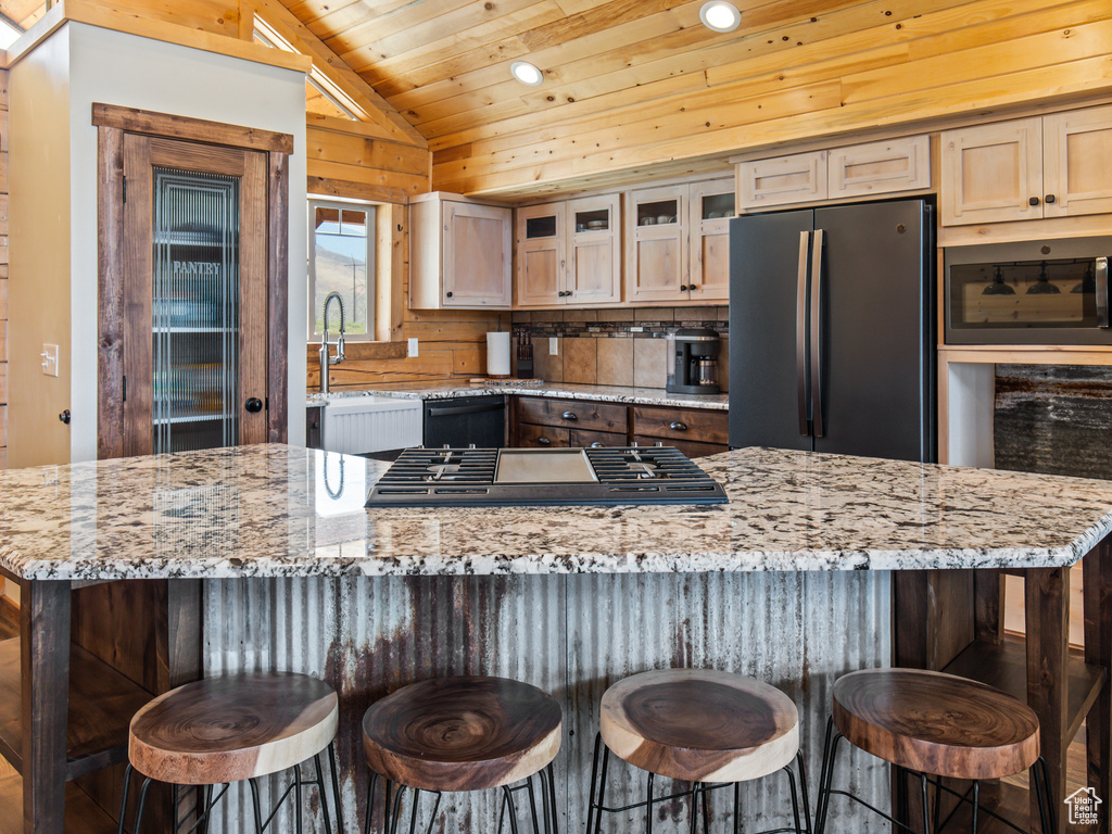 Kitchen with backsplash, stainless steel fridge, vaulted ceiling, and a breakfast bar