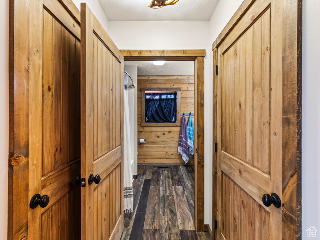 Corridor featuring dark wood-type flooring and wood walls