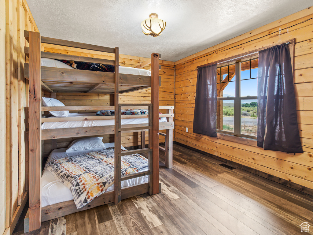 Bedroom with wood walls, a textured ceiling, and hardwood / wood-style flooring