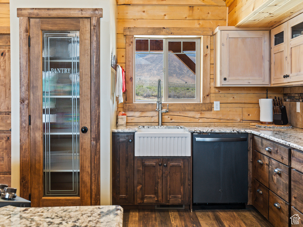 Kitchen with wooden walls, sink, dark hardwood / wood-style floors, light stone countertops, and dishwasher