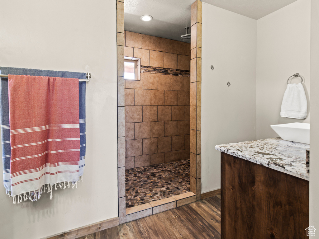 Bathroom featuring tiled shower, hardwood / wood-style floors, and vanity