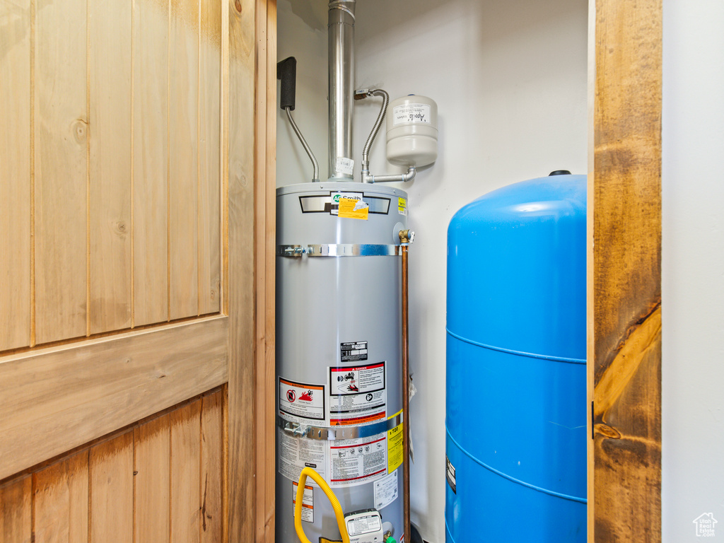 Utility room featuring strapped water heater