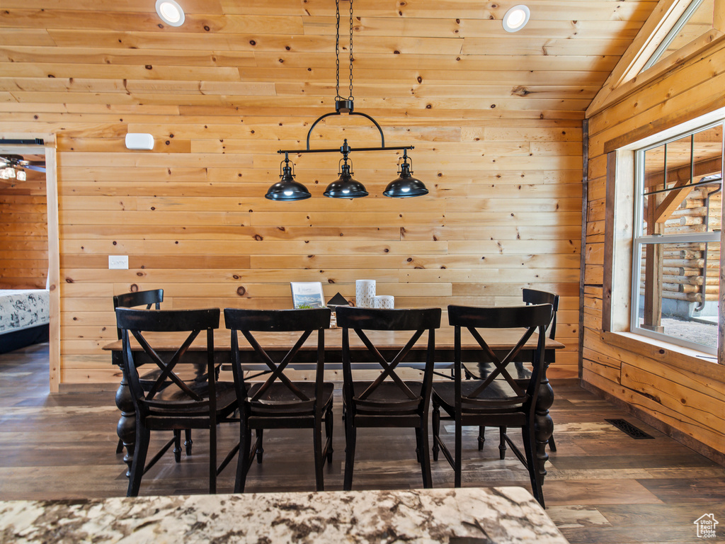 Dining room with wood walls, lofted ceiling, and dark hardwood / wood-style floors