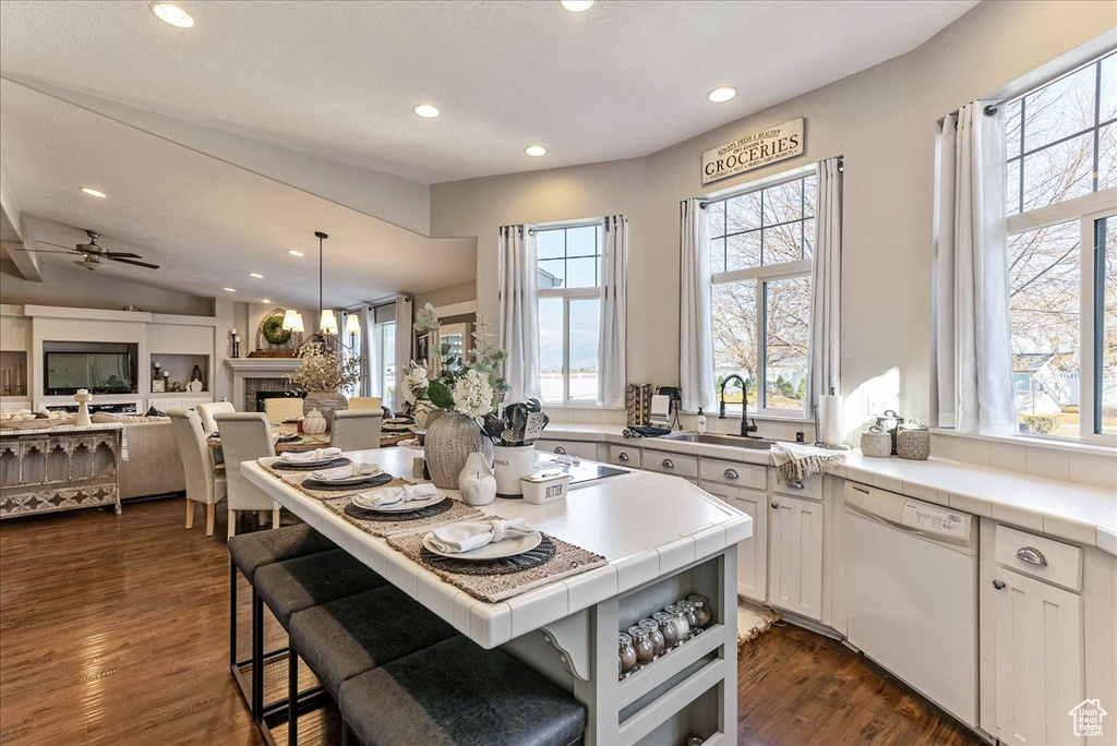 Kitchen with white cabinets, sink, white dishwasher, a center island, and dark hardwood / wood-style floors