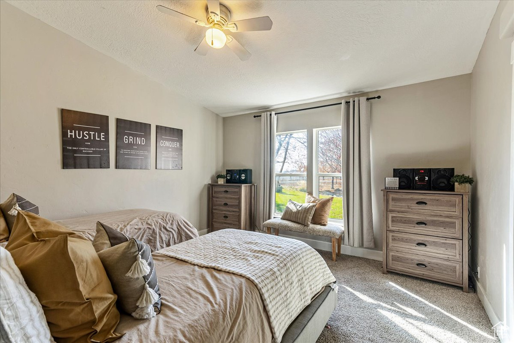 Carpeted bedroom featuring ceiling fan and vaulted ceiling