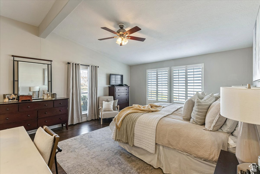 Bedroom with dark hardwood / wood-style floors, vaulted ceiling with beams, and ceiling fan