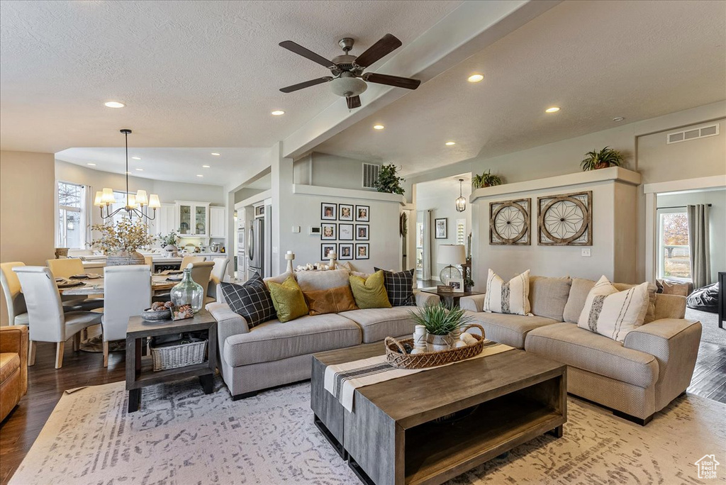 Living room featuring a textured ceiling, ceiling fan with notable chandelier, and hardwood / wood-style floors