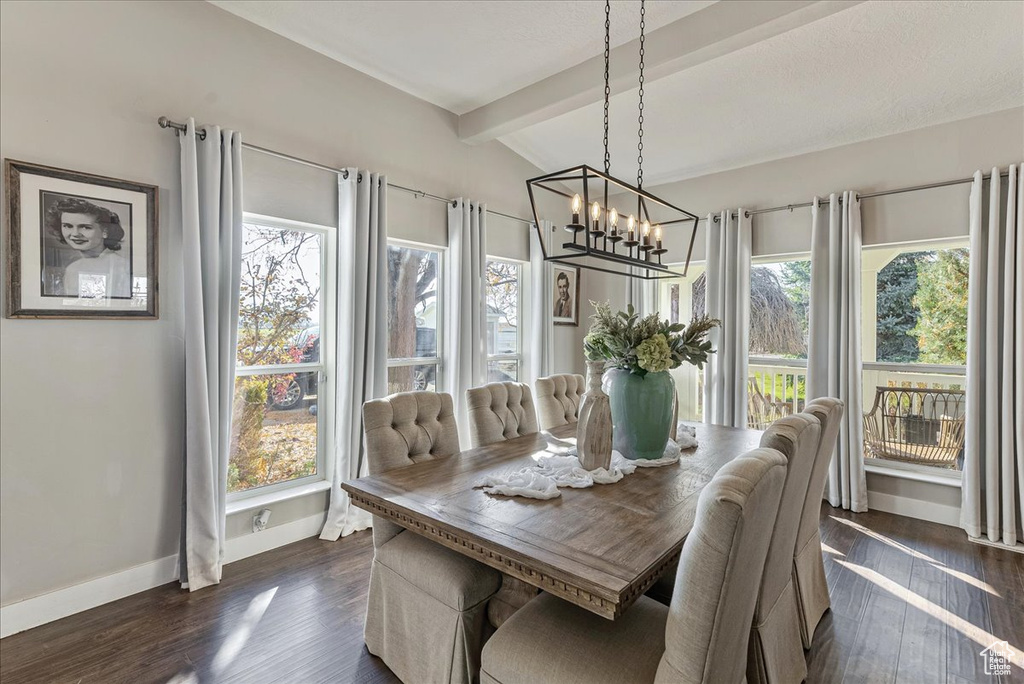 Dining area with lofted ceiling with beams, dark hardwood / wood-style floors, and a notable chandelier