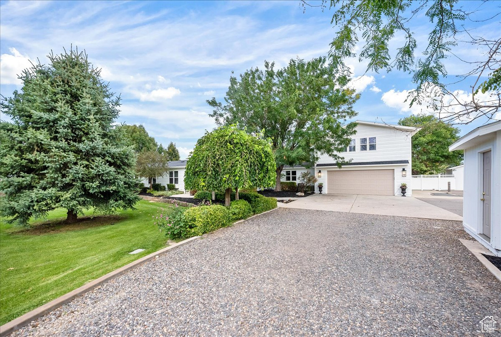 View of property hidden behind natural elements with a garage and a front lawn