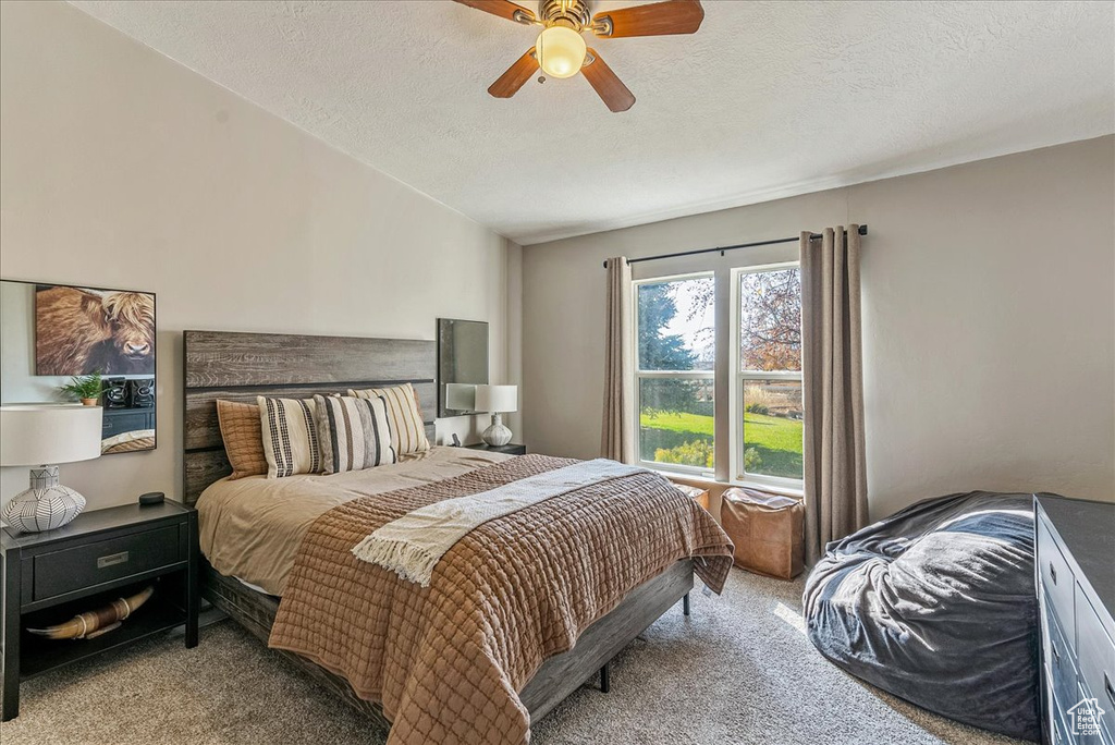 Carpeted bedroom with a textured ceiling and ceiling fan