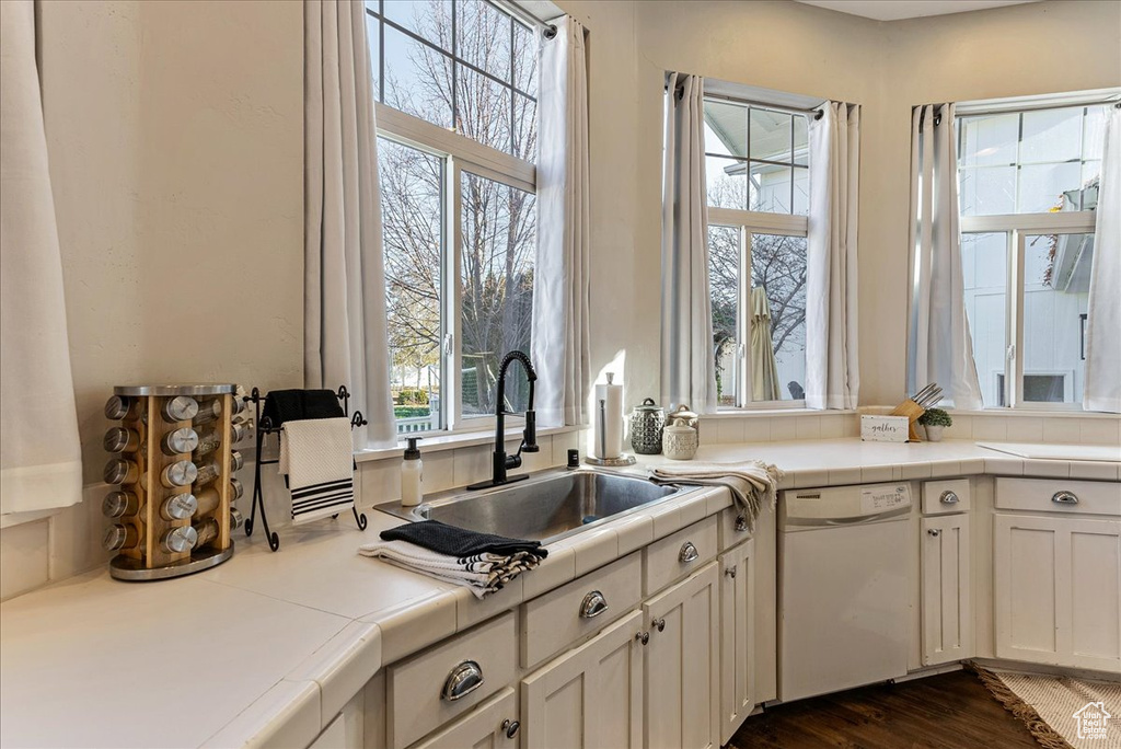 Kitchen featuring dark hardwood / wood-style floors, white dishwasher, tile countertops, and sink