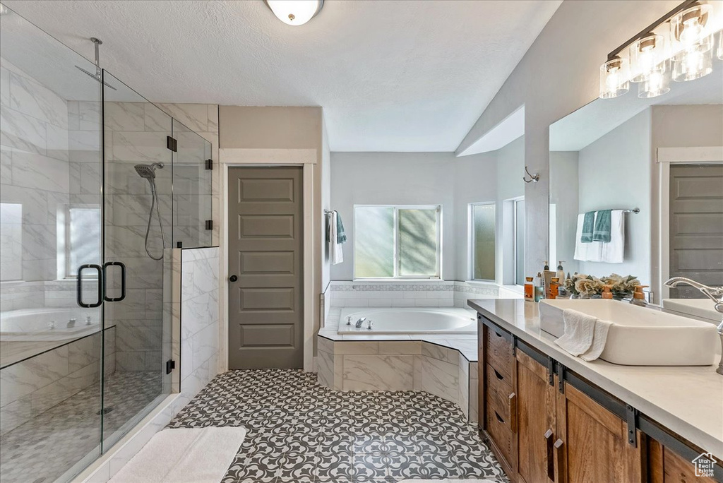 Bathroom with tile patterned flooring, separate shower and tub, vaulted ceiling, and vanity