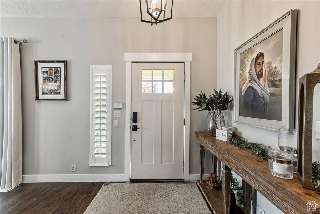 Entrance foyer with an inviting chandelier, a textured ceiling, and dark hardwood / wood-style floors