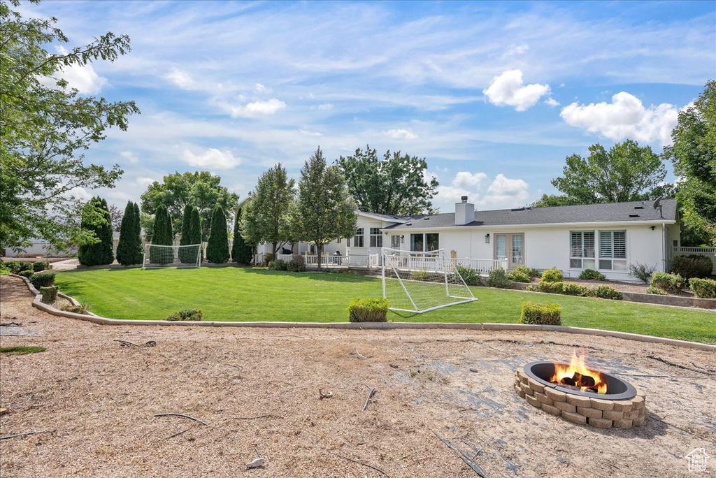 Rear view of property featuring a yard and an outdoor fire pit