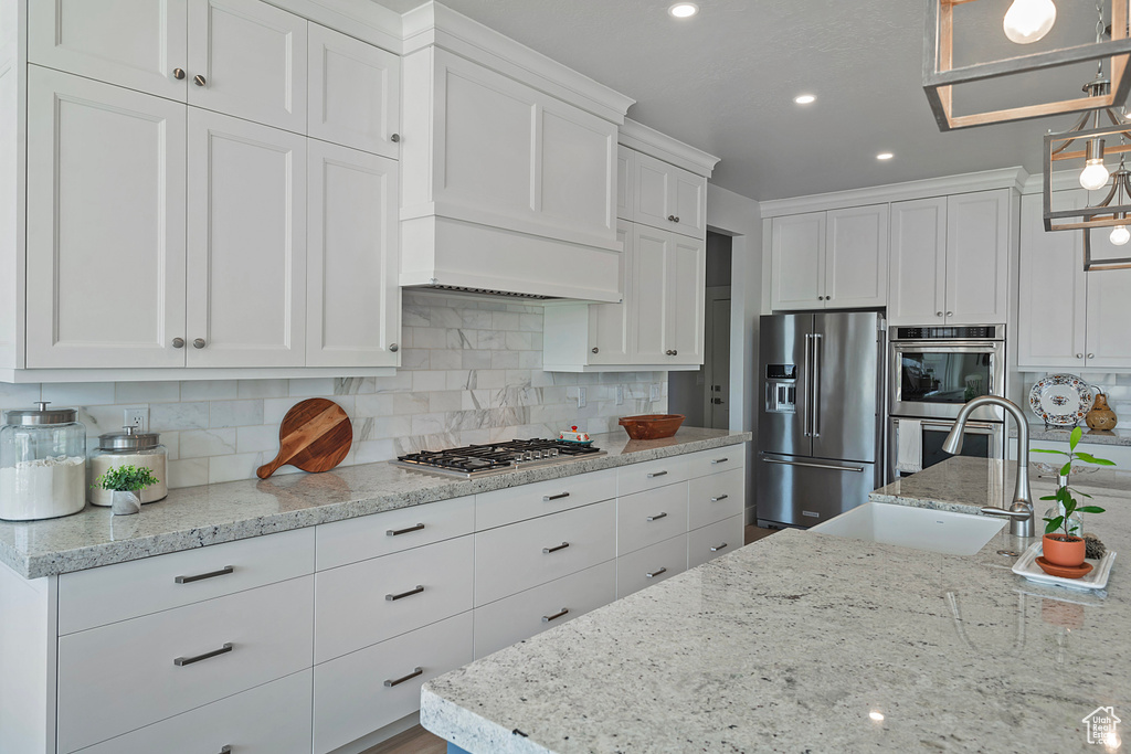 Kitchen with white cabinets, stainless steel appliances, tasteful backsplash, and pendant lighting