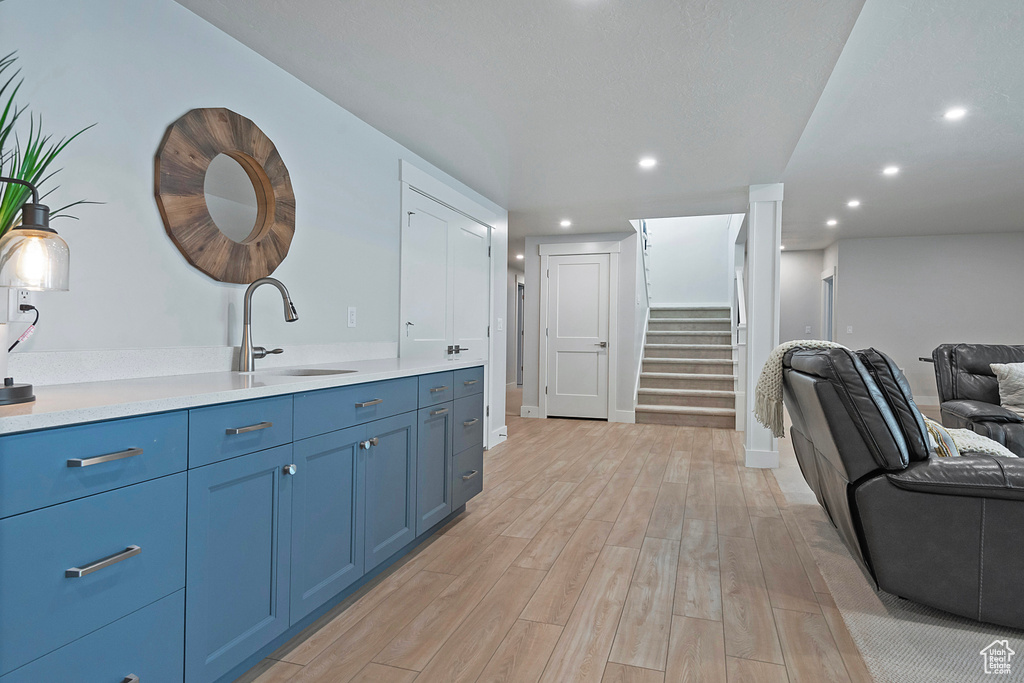 Interior space with sink, blue cabinetry, and light wood-type flooring