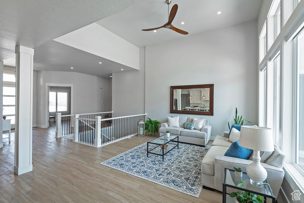 Living room with ceiling fan, hardwood / wood-style floors, and a high ceiling