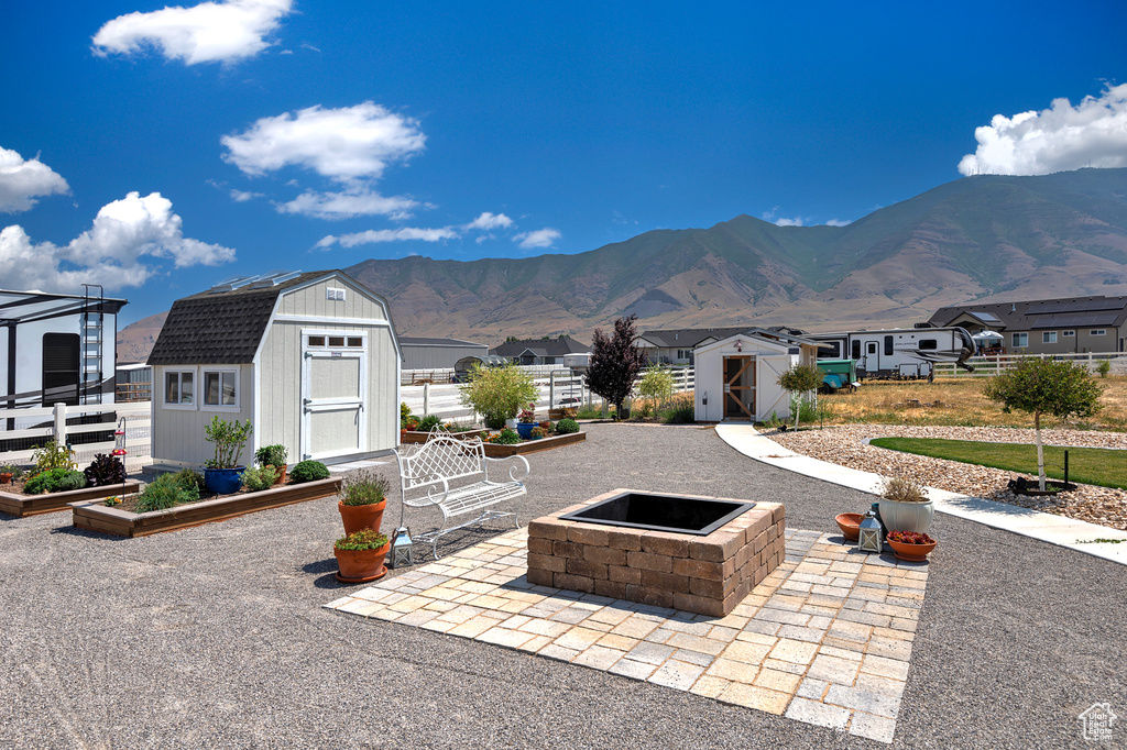 View of patio / terrace with a storage shed, a mountain view, and a fire pit